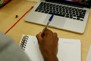hand taking notes in front of laptop