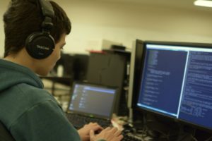 man coding at a laptop and external monitor